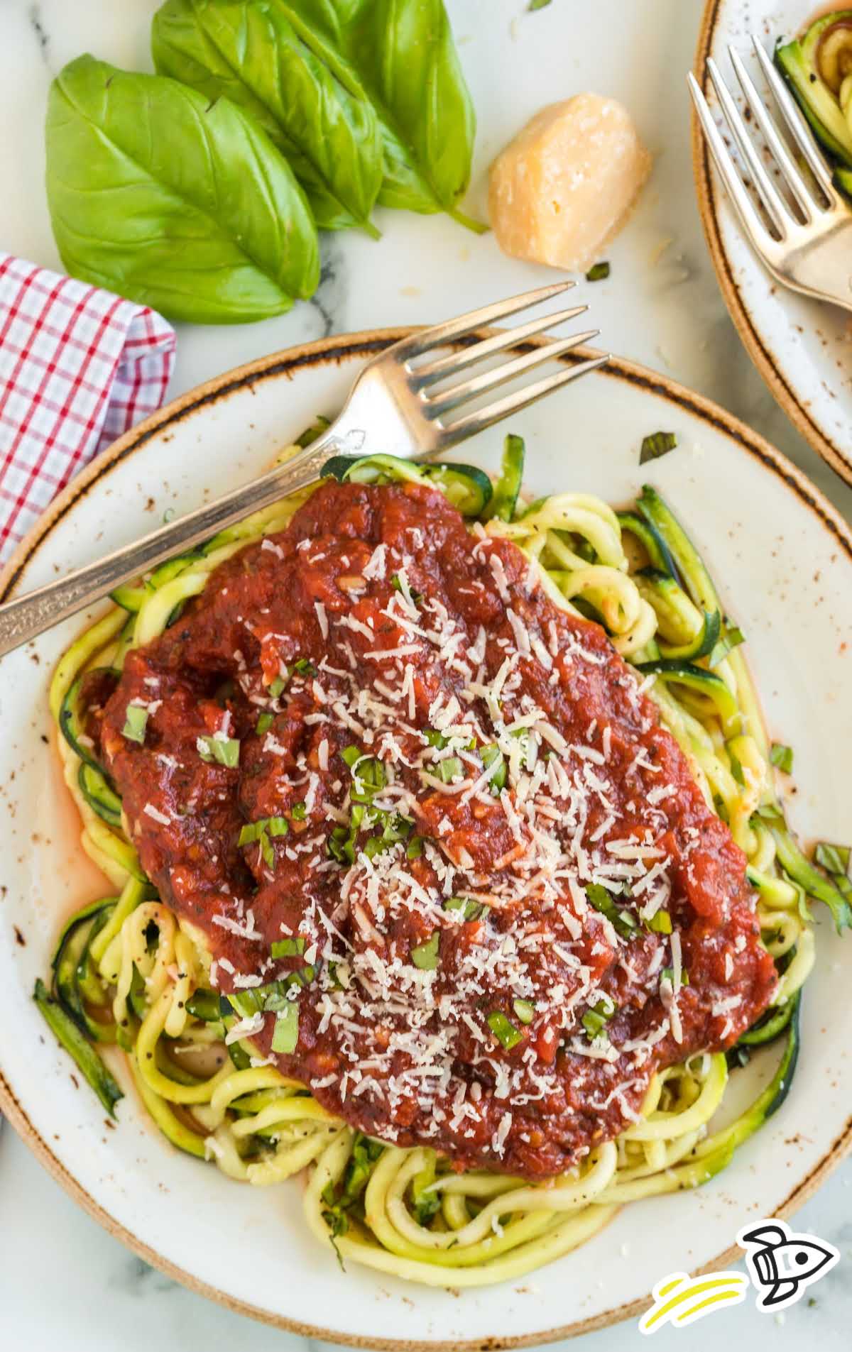 a plate of zucchini noodles topped with pasta sauce served with a fork