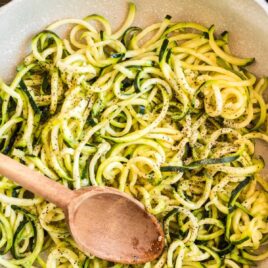 close up overhead shot of Zucchini Noodles in a bowl with a wooden spoon