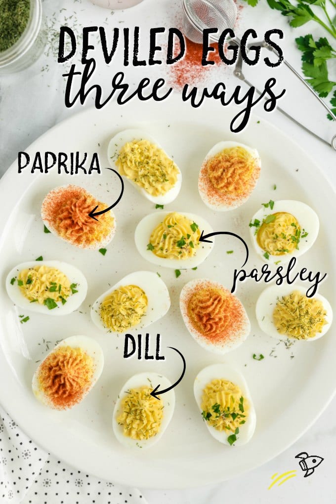 white plate with three different types of deviled eggs: paprika, parsley, and dill