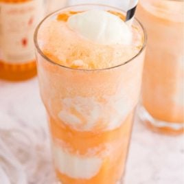 close up shot of a glass of boozy creamsicle float with a straw