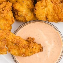 close up overshot of chicken finger dipping sauce in a bowl with a chicken tender being dipped into it