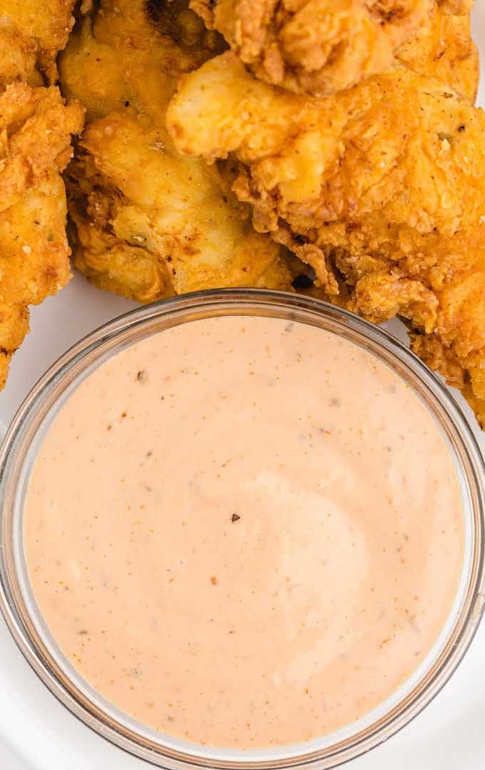 close up overshot of chicken finger dipping sauce in a bowl with chicken tenders on the side