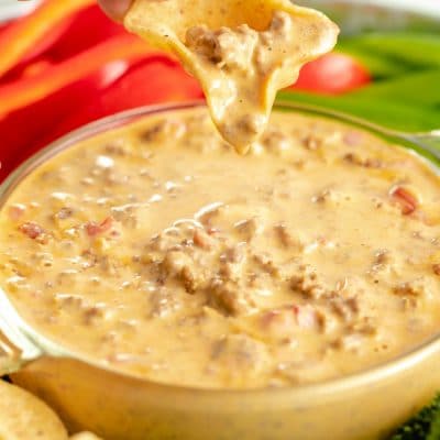 cheese Rotel dip in a bowl with a chip being dipped