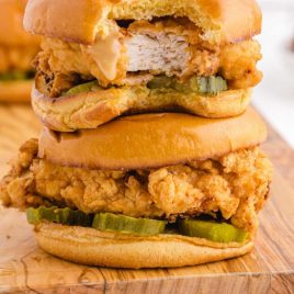 close up shot of fried chicken sandwich stacked on top of each other on a wooden board