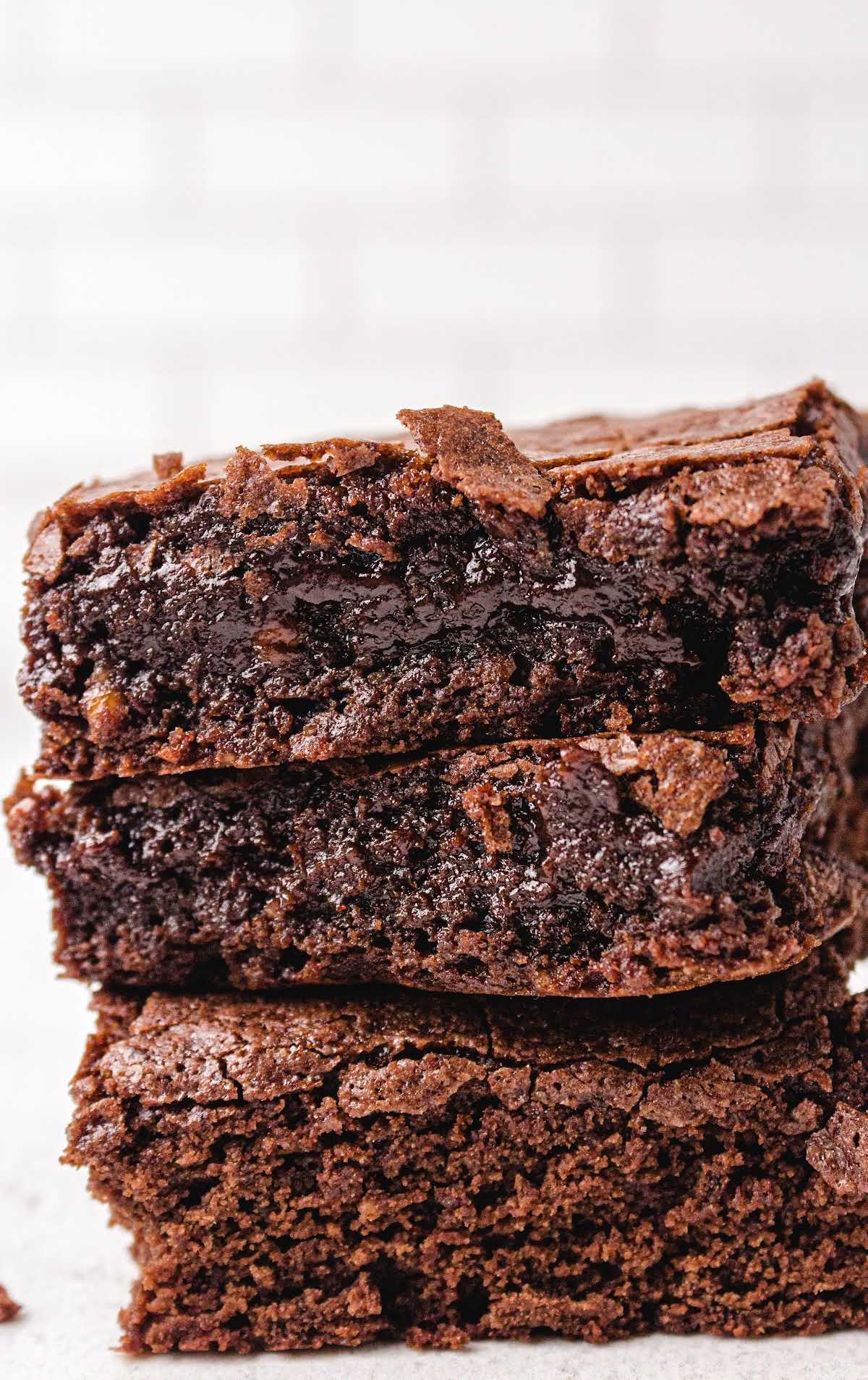 Fudgy egg white brownies stacked on a light background with shiny chocolate center