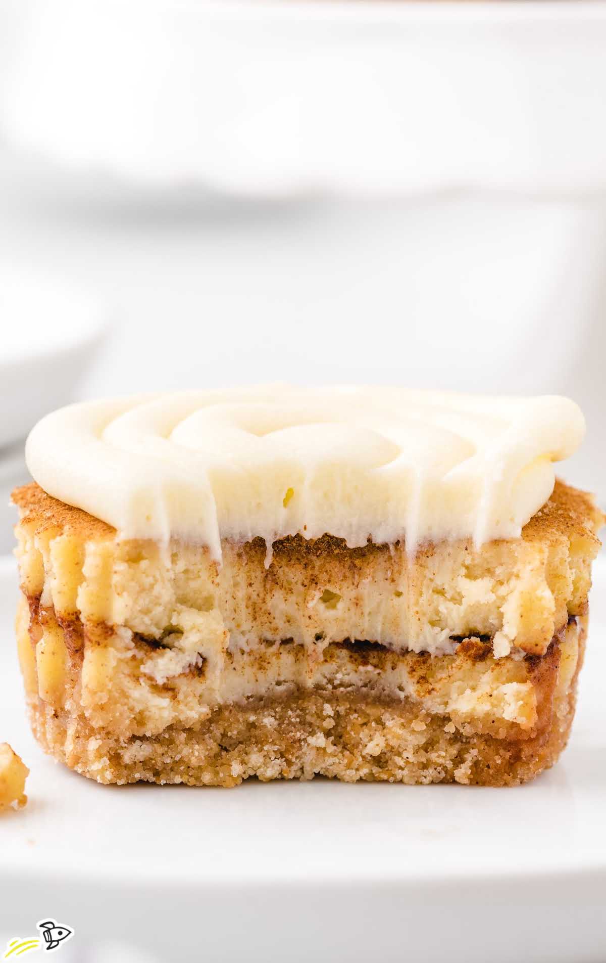 Mini cinnamon roll cheesecakes arranged on a serving plate with cream cheese frosting swirled on top