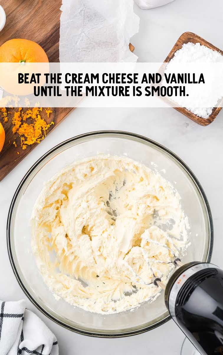 cream cheese and vanilla being blended in a bowl