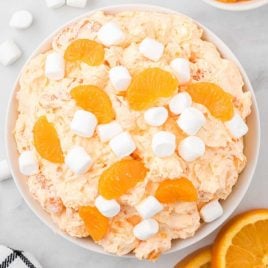 close up overhead shot of a bowl of orange creamsicle salad topped with mandarin oranges and mini marshmallows