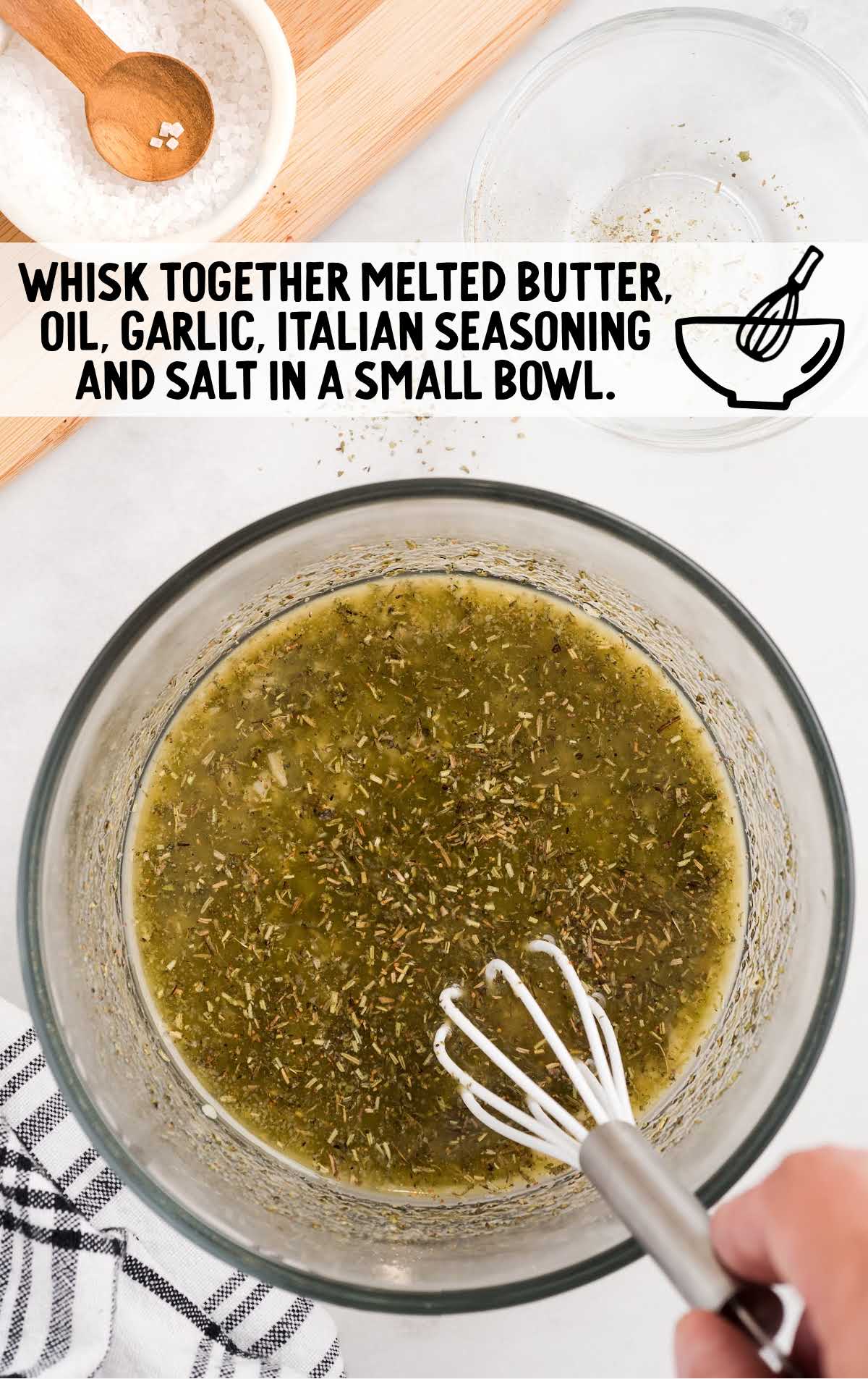 melted butter, oil, and seasonings being whisked together in a bowl