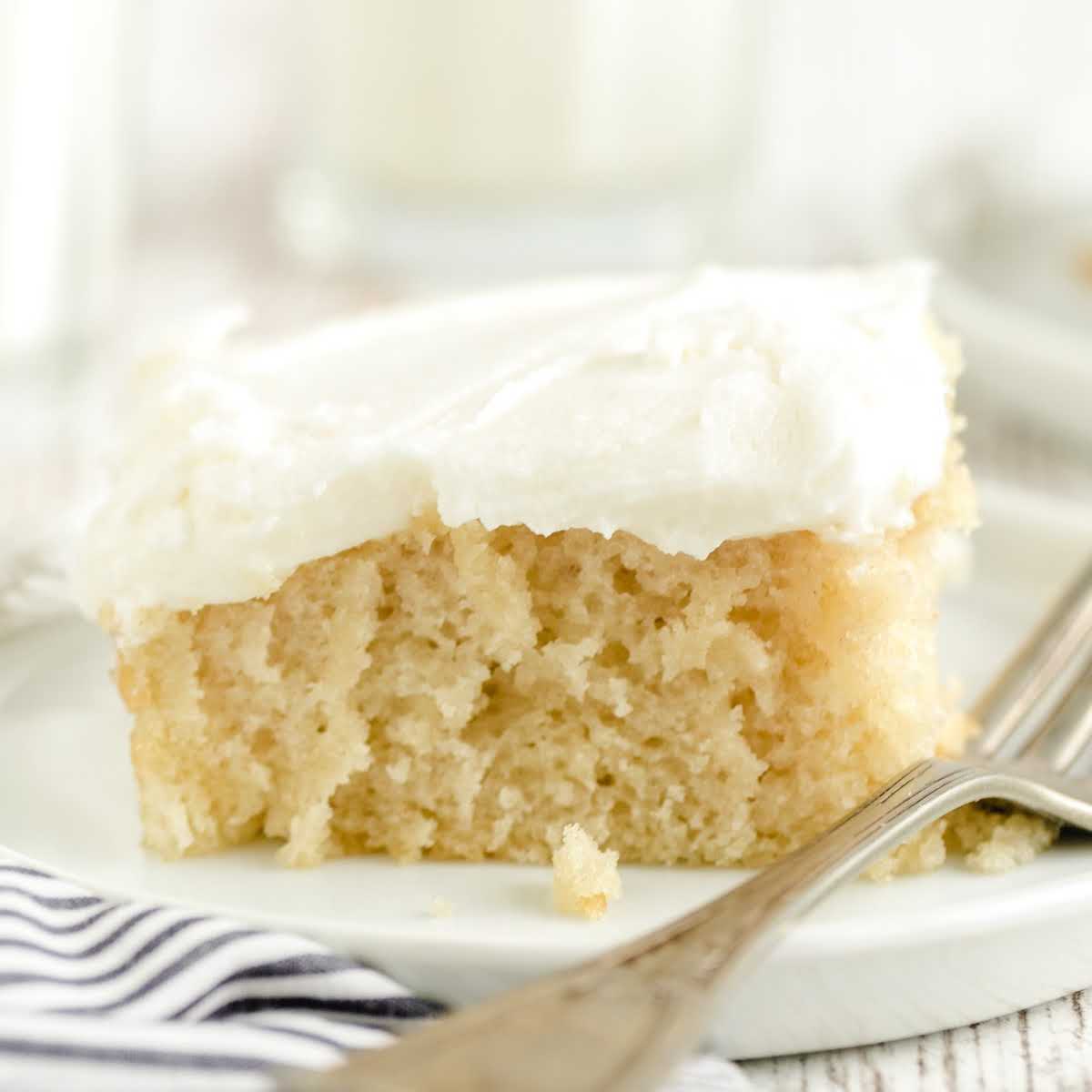 Slice of vanilla crazy cake with white frosting served on a small white plate, styled for a recipe card format.