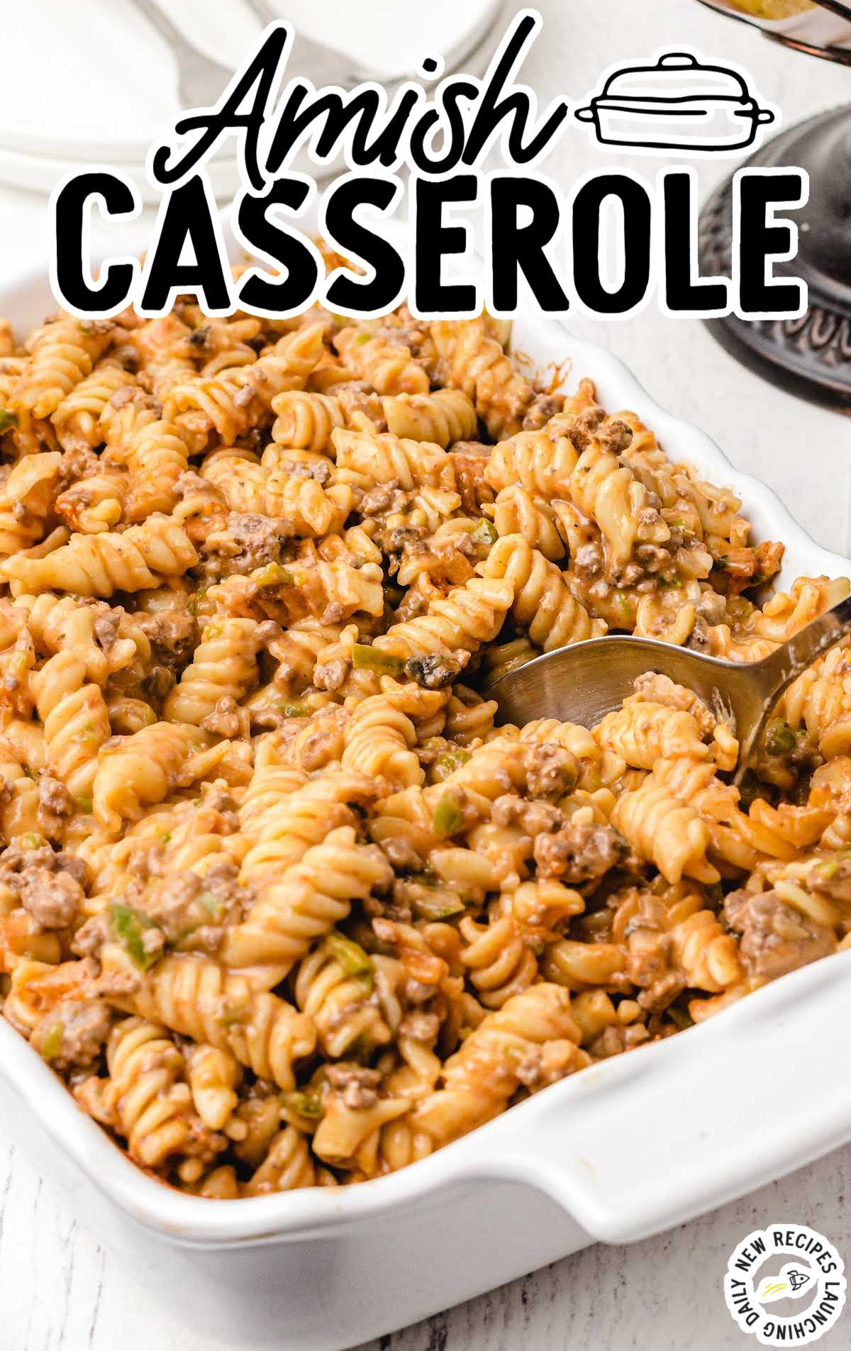 Overhead shot of baked Amish casserole in a white dish with rotini pasta, ground beef, and creamy tomato sauce.