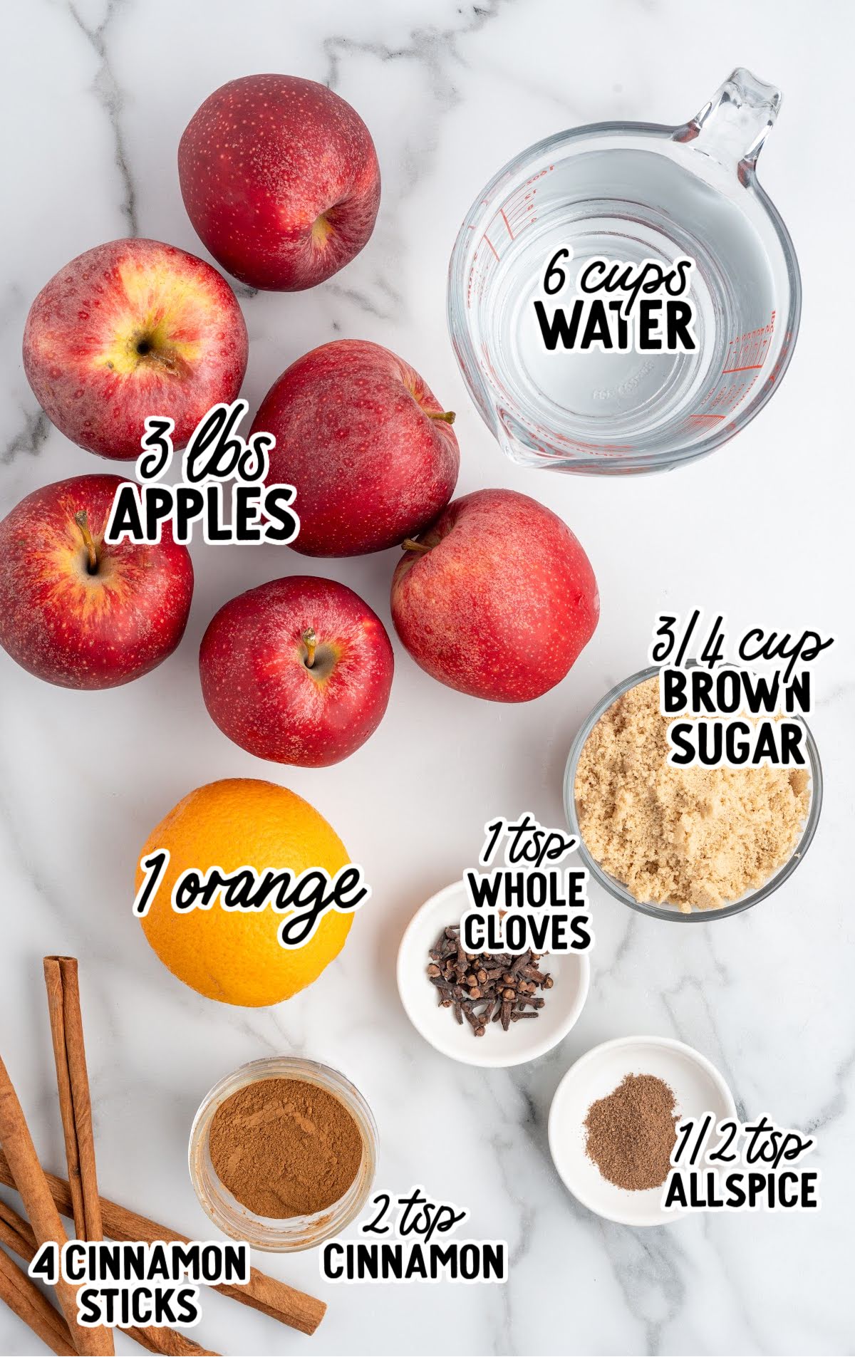 Flat lay of apples, orange, brown sugar, cinnamon, cloves, and allspice labeled for apple cider recipe.