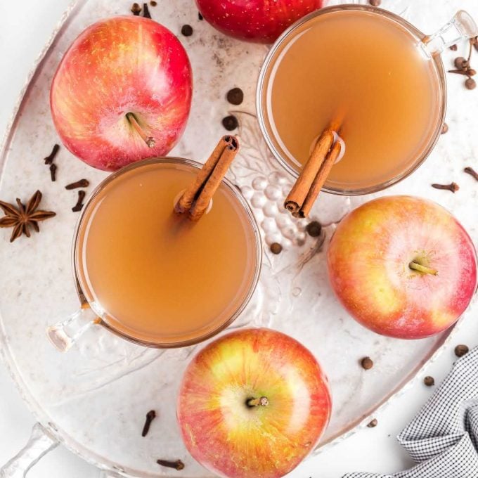 close up overhead shot of glasses of Apple Cider with cinnamon sticks and apples on the side