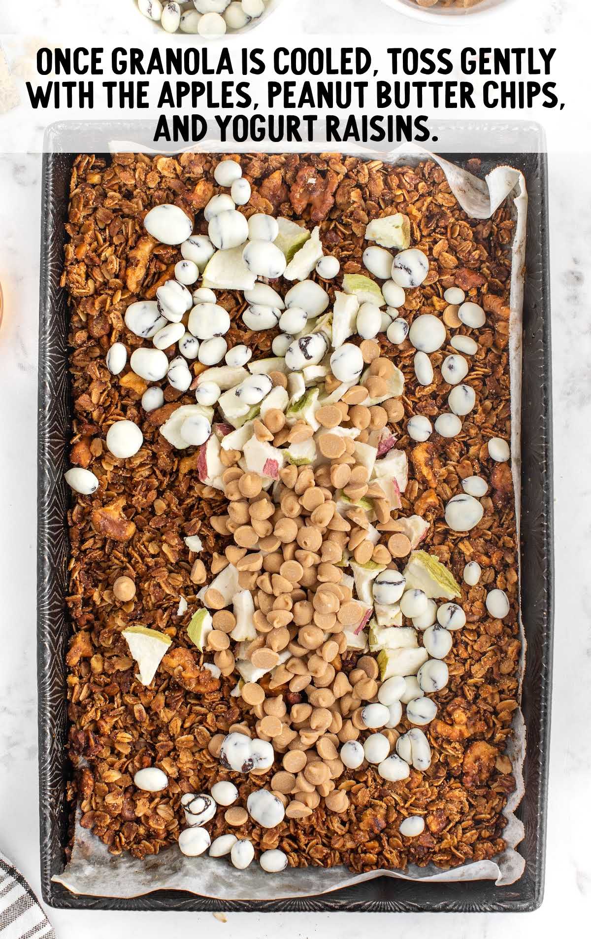 apple cinnamon granola process shot of granola topped with ingredients in a baking tray