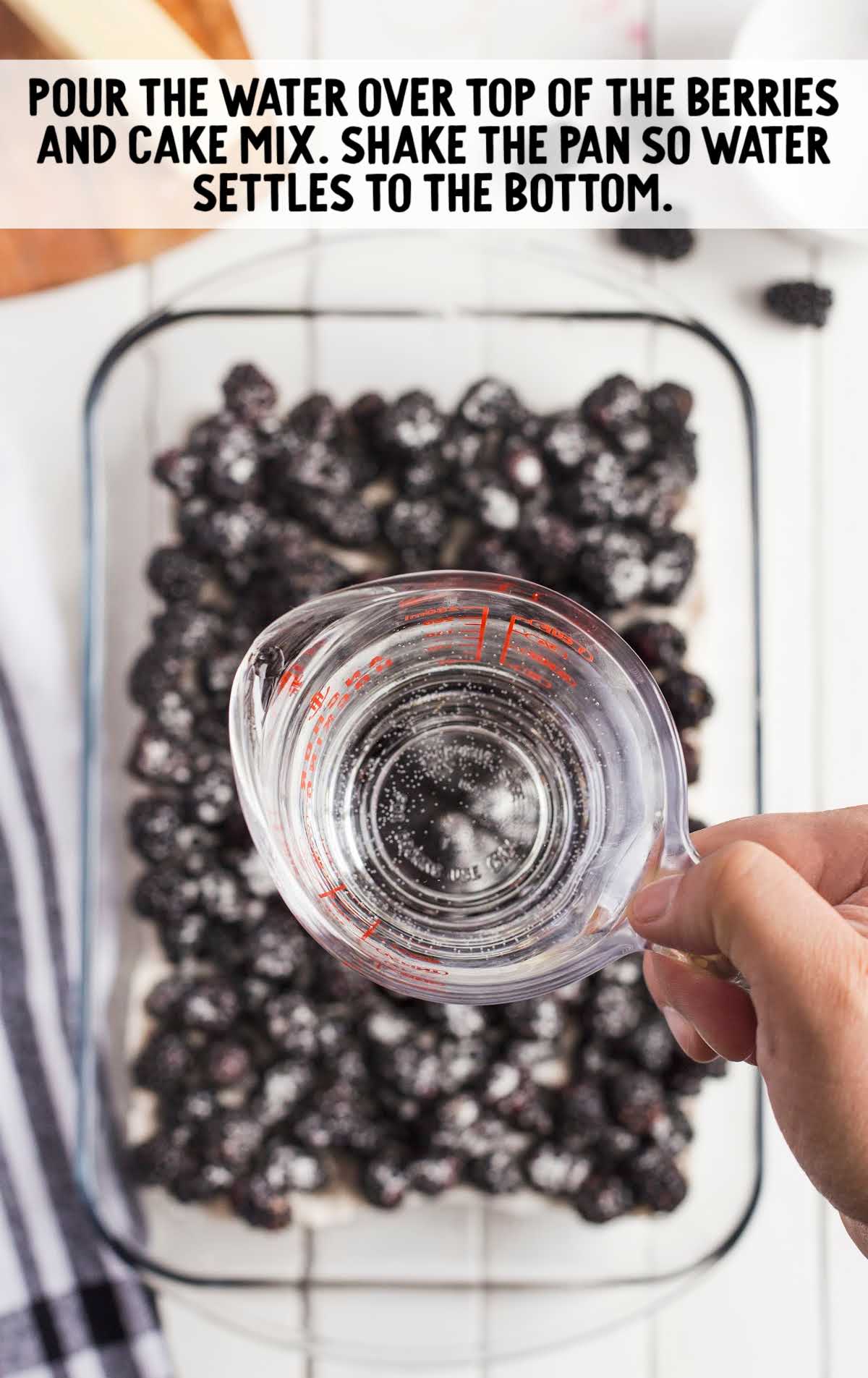 water poured on top of blackberries in a baking dish