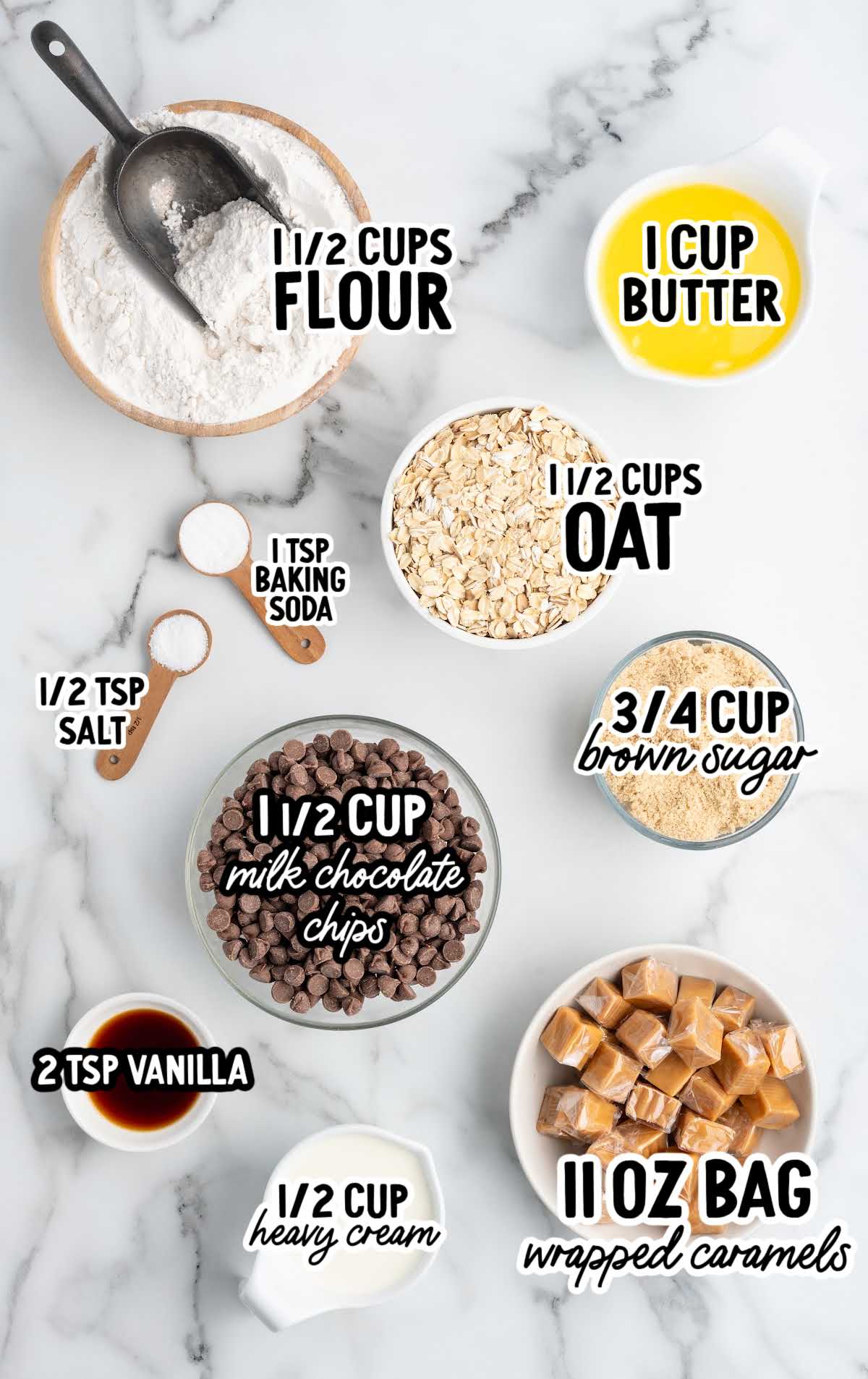 Overhead shot of measured ingredients for Carmelitas including flour, oats, butter, brown sugar, chocolate chips, vanilla, salt, baking soda, cream, and wrapped caramels.
