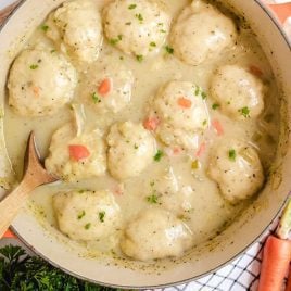close up overhead shot of a pot of Chicken and Dumplings with a large wooden spoon