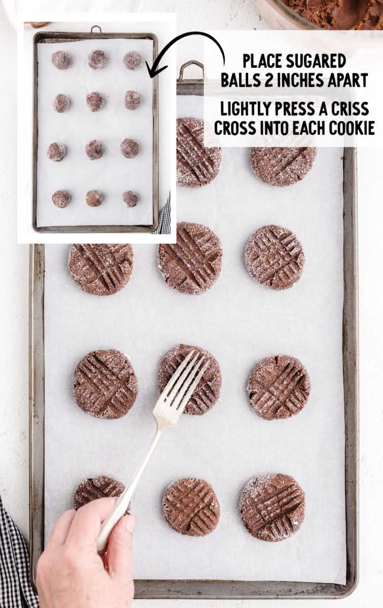 criss cross indent being made on cookie dough balls on a baking sheet