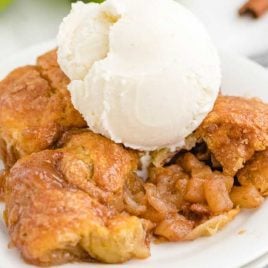 close up shot of a serving of easy apple dumplings topped with vanilla ice cream on a plate