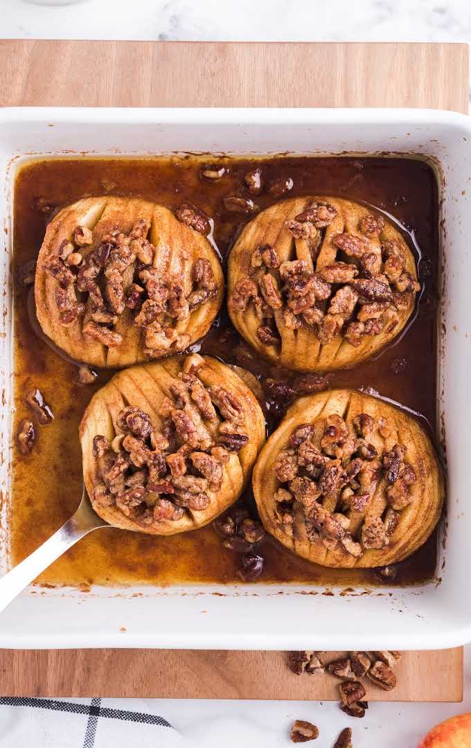 close up overhead shot of hasselback apples topped with pecans in a baking dish