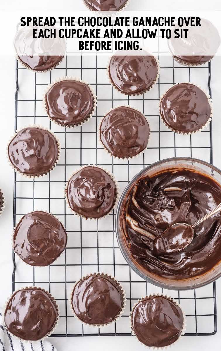 chocolate ganache being spread over cupcakes