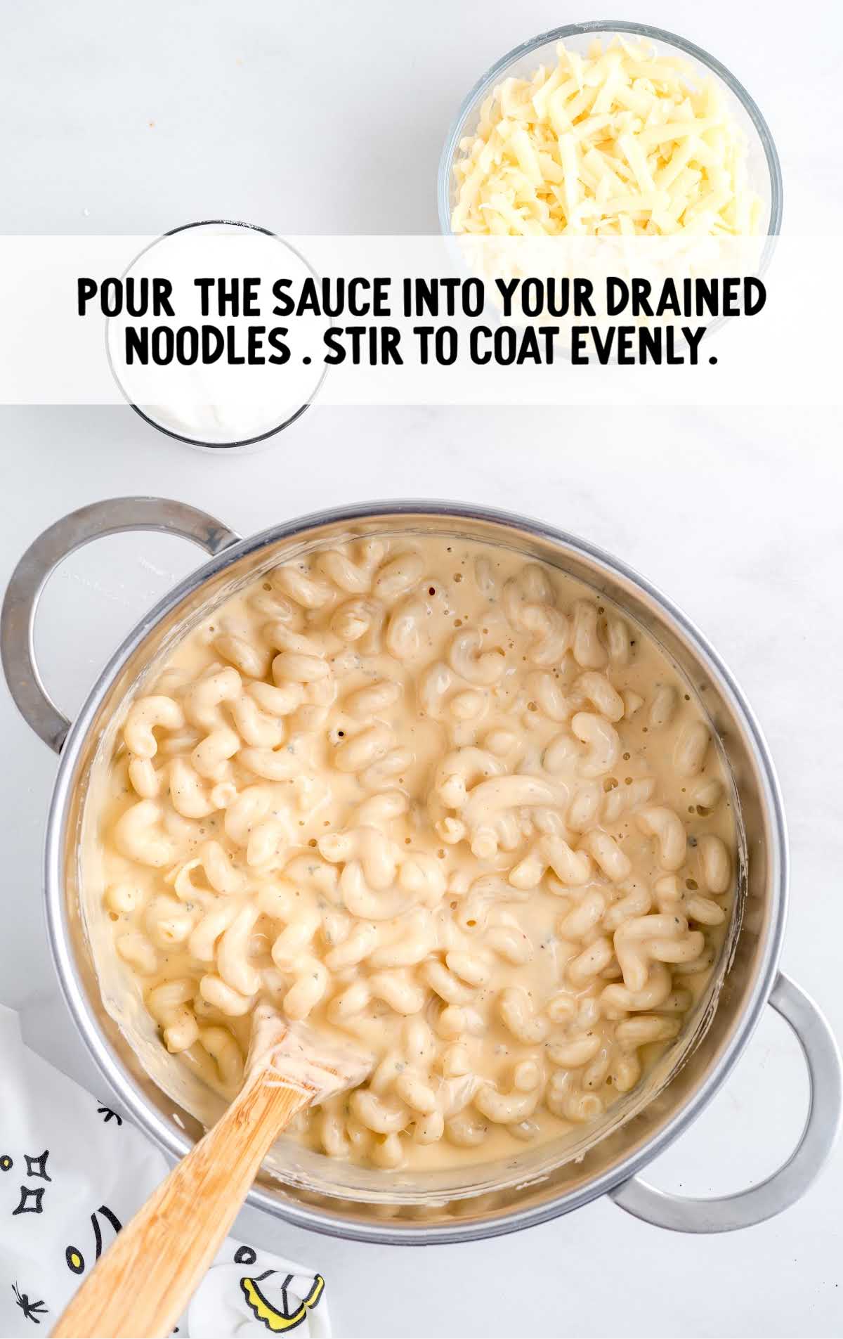 sauce being poured on cooked noodles and mixed together in a pot