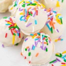 close up shot of No Bake Cheesecake Bites topped with sprinkles on a plate