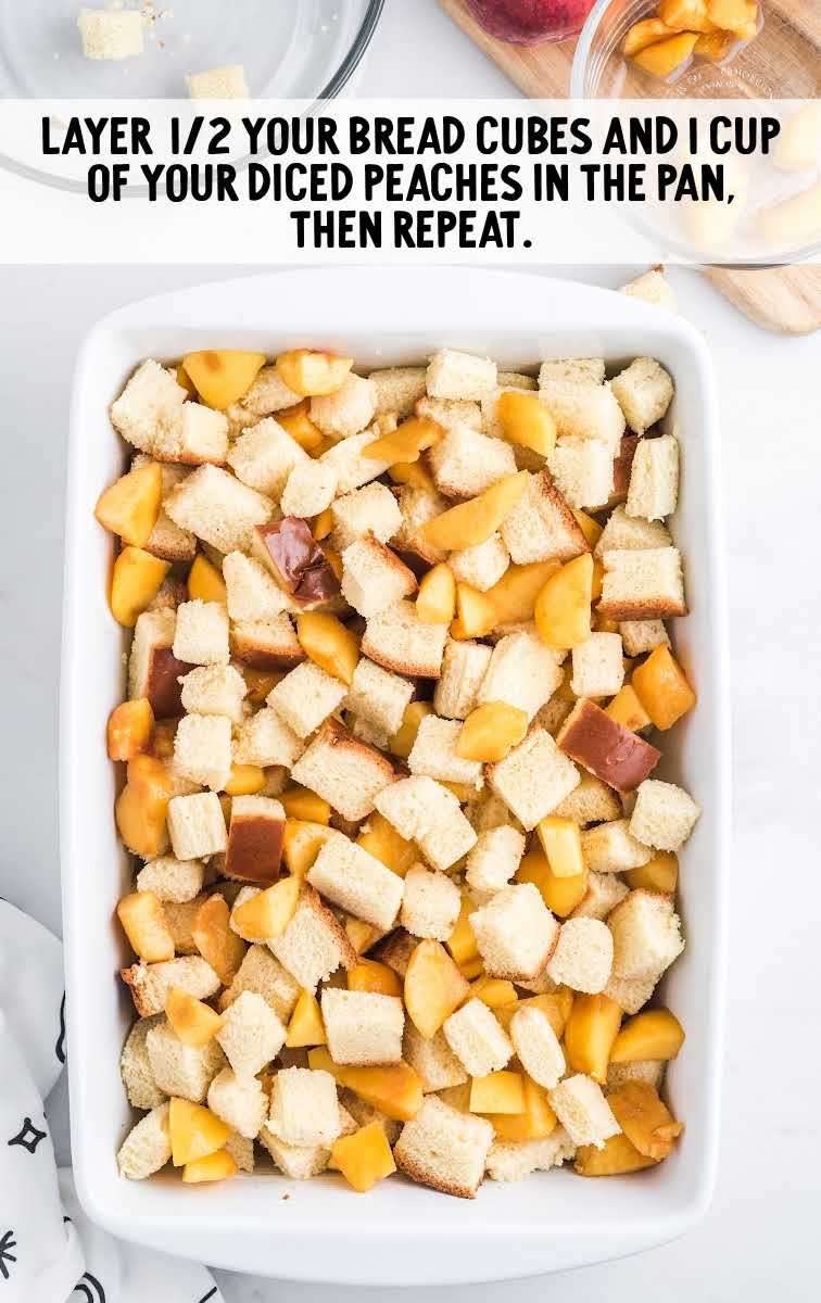 baking dish being filled with bread cubes and diced peaches