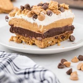 corner shot of a slice of a peanut butter dream bar on a white plate