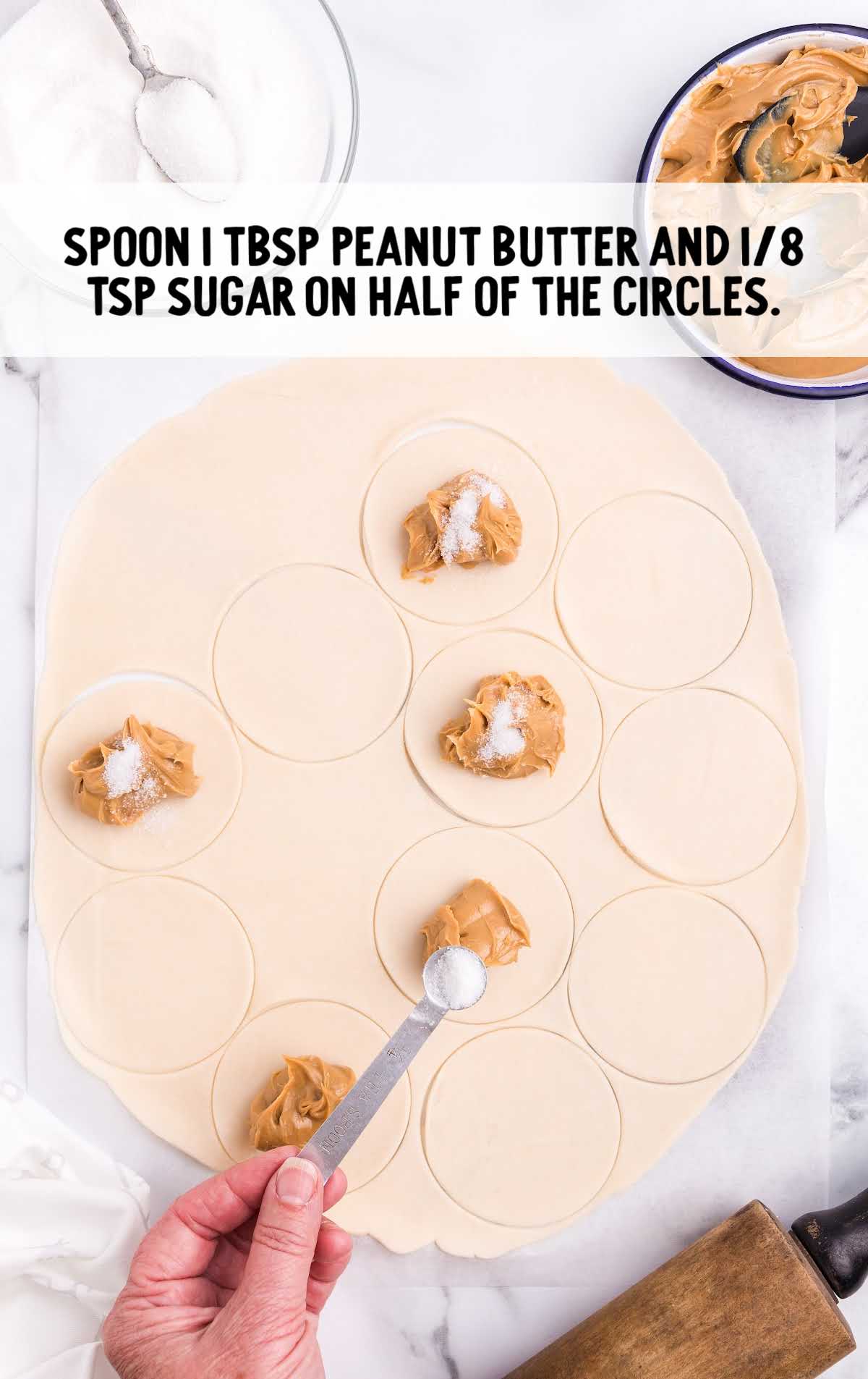 peanut butter and sugar being placed on to dough circles