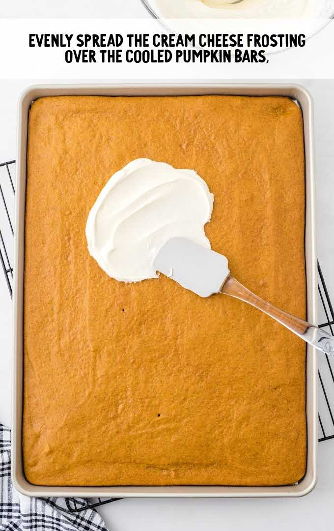 cream cheese frosting being spread over pumpkin bars