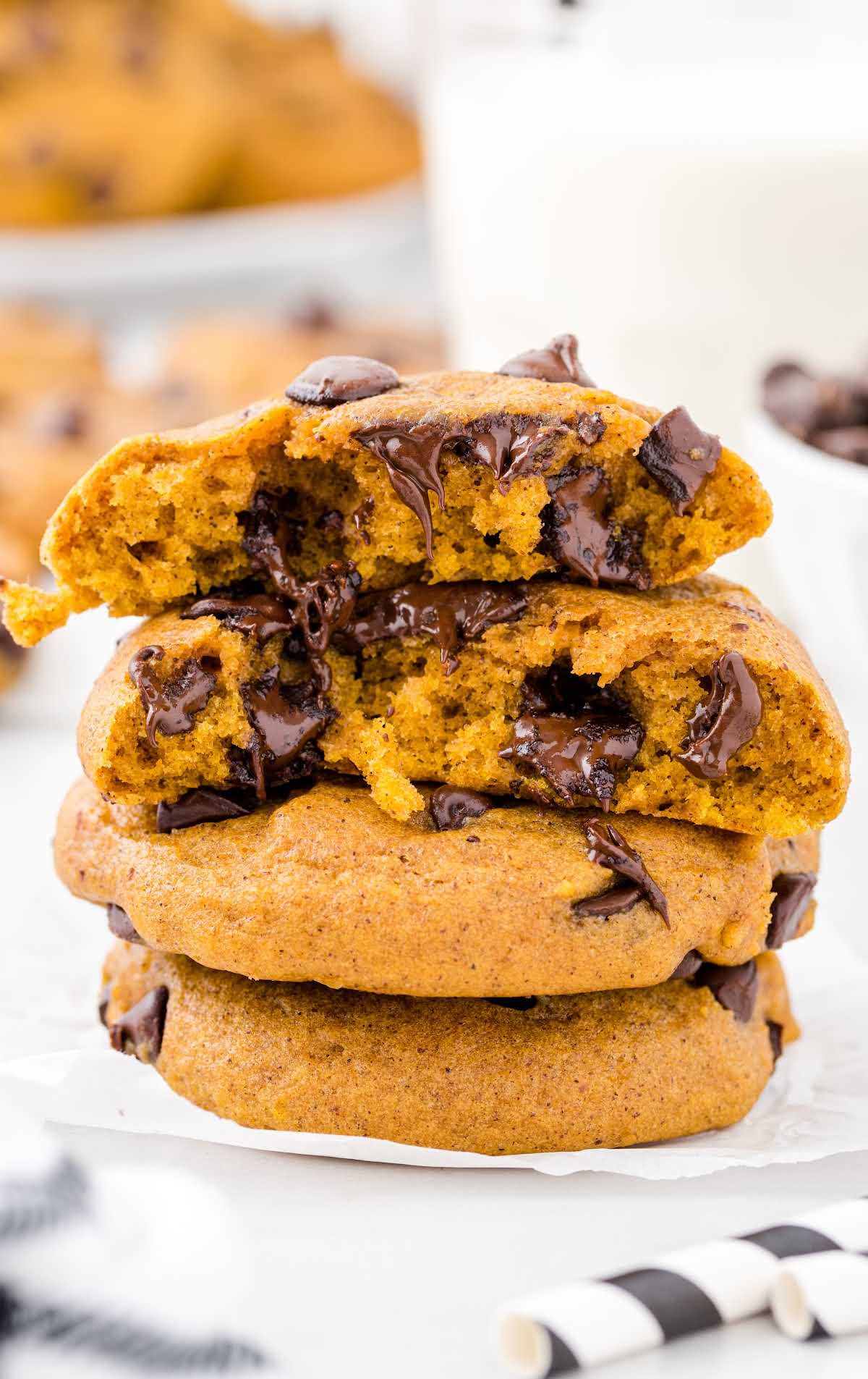 Pumpkin Chocolate Chip Cookies stacked on top of each other with a bite taken out of them