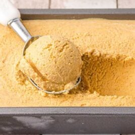 a scoop of pumpkin ice cream in a ice cream scooper and in a pan