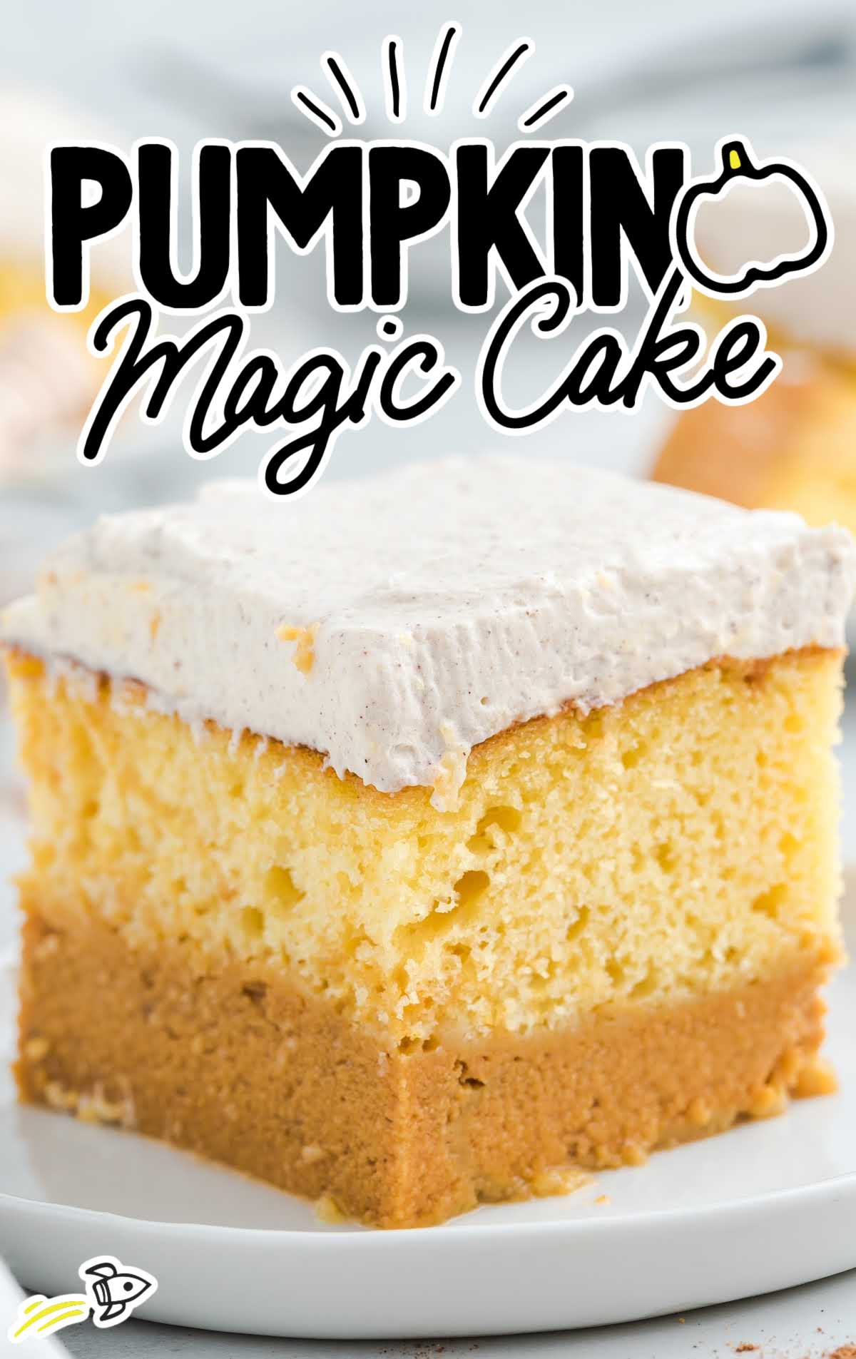 Pumpkin magic cake slice on a white plate with visible pumpkin base layer and whipped topping.