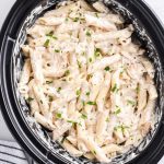 close up shot of Slow Cooker Olive Garden Chicken Pasta topped with parsley in a crockpot