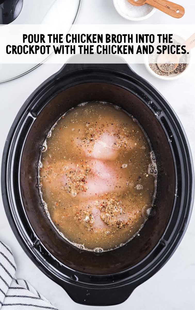 chicken broth poured into the crockpot with the chicken and spices 