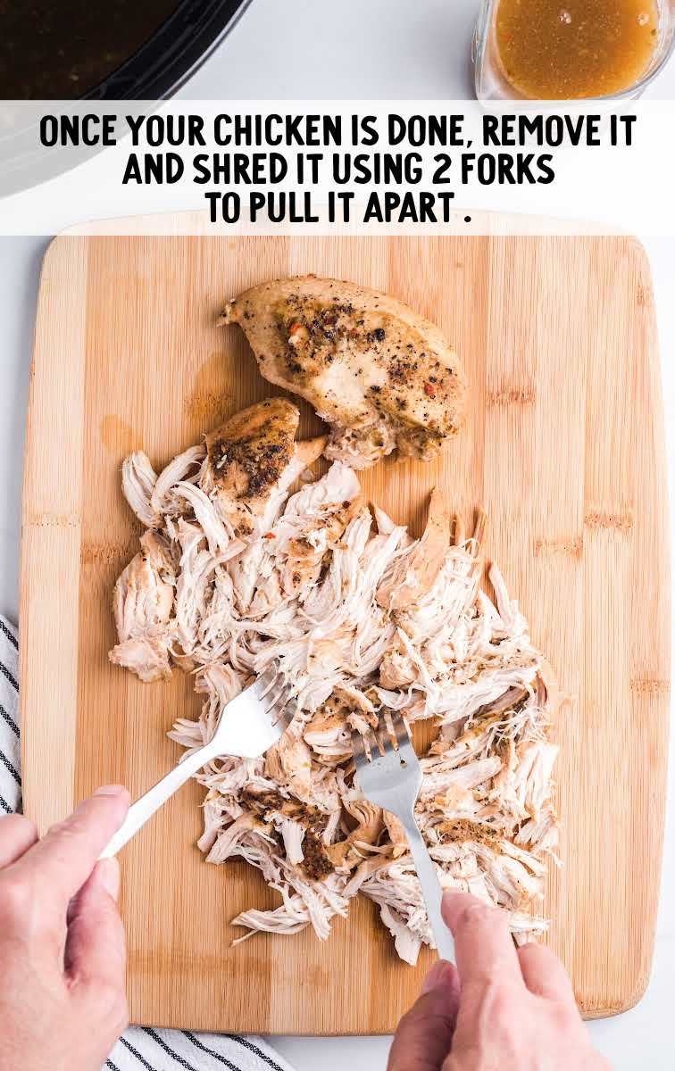 chicken being shredded on a wooden board