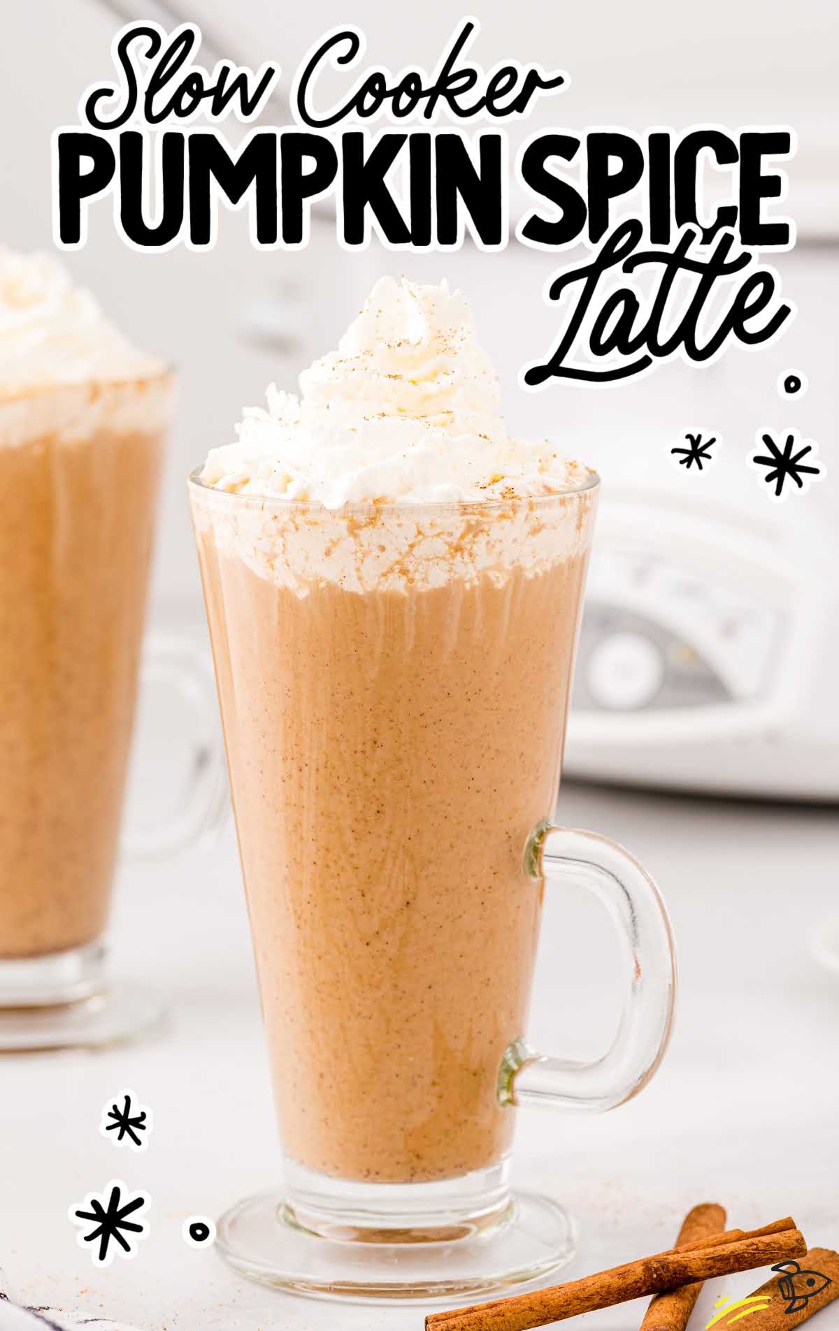 Glass mug of slow cooker pumpkin spice latte topped with whipped cream and sprinkled spices.