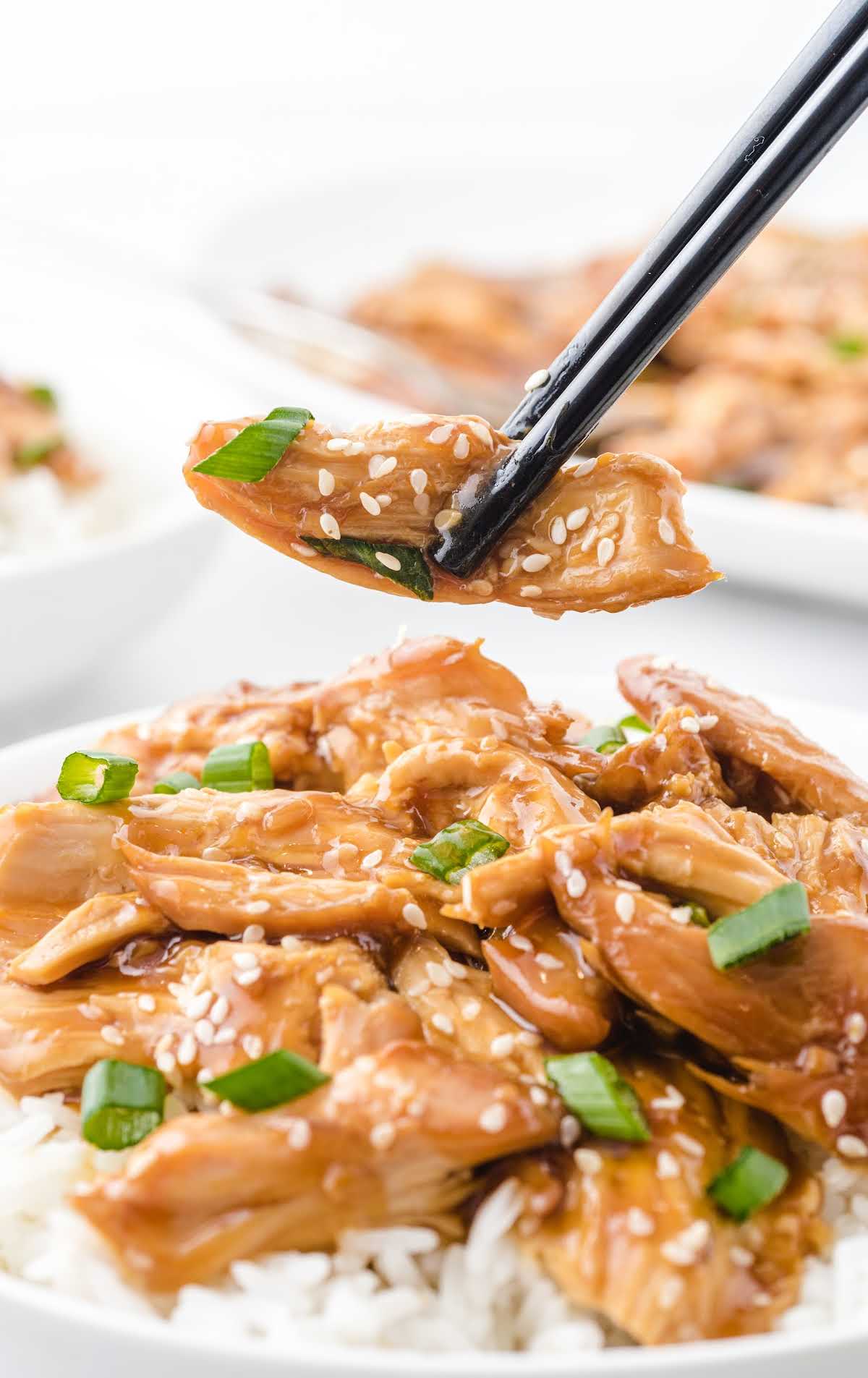 Slow cooker teriyaki chicken served over rice with sesame seeds and sliced green onions