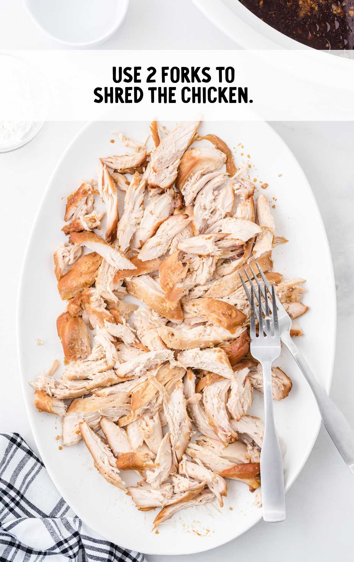 Cooked chicken breasts shredded with two forks for slow cooker teriyaki chicken
