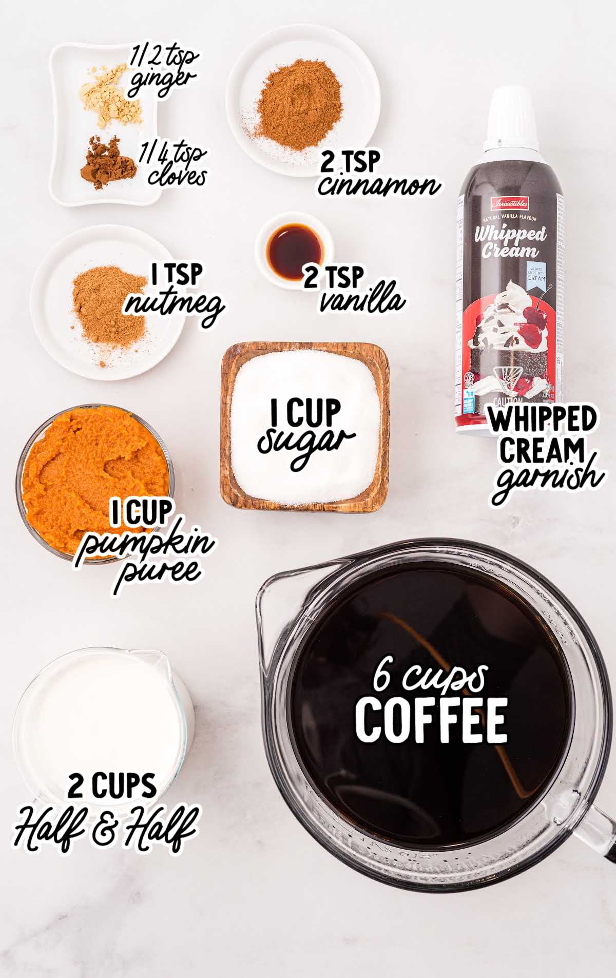 Flat lay of pumpkin spice latte ingredients including pumpkin puree, coffee, half and half, sugar, vanilla, and spices.