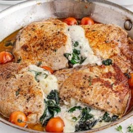 close up shot of Stuffed Pork Chops with cherry tomatoes and spinach in a pot