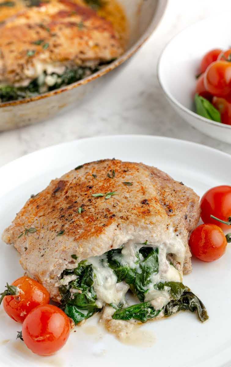 close up shot of Stuffed Pork Chops with cherry tomatoes and spinach on a plate