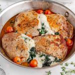 close up shot of Stuffed Pork Chops with cherry tomatoes and spinach in a pot