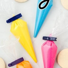 yellow, pink, blue, and orange icing in piping bags