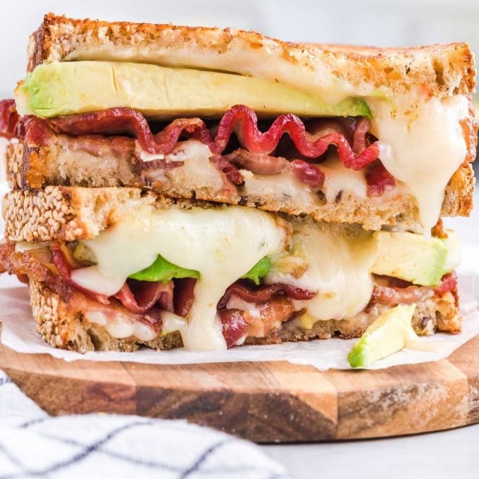 close up shot of slices of a bacon avocado sandwich stacked one top of each other on a wooden board