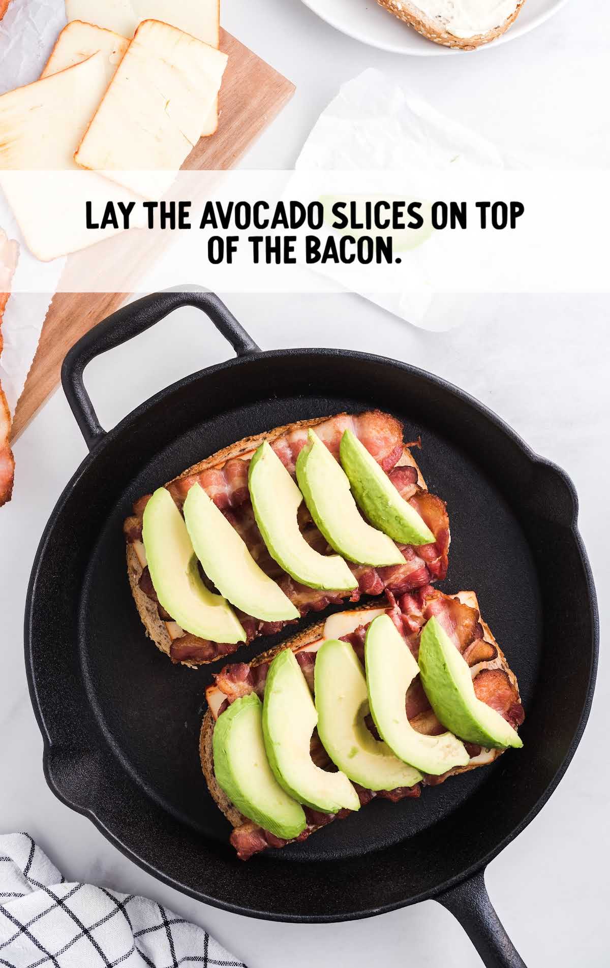 bacon avocado sandwich process shot of avocado slices being layer on top of bacon in a skillet