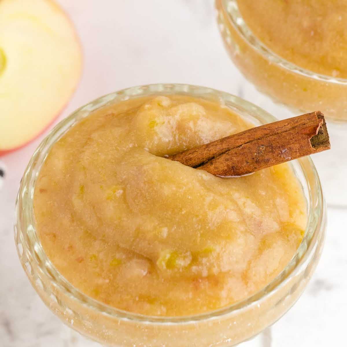 close up shot of a bowl of crockpot applesauce with a cinnamon stick