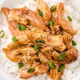 slow cooker teriyaki chicken served over white rice and topped with sesame seeds and sliced green onions
