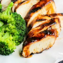 a plate of grilled chicken topped with beer marinade topped with bbq sauce and served with a side of broccoli